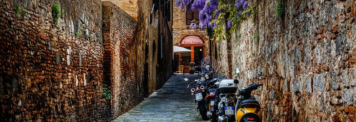 Motorcycles parked along brick wall in Siena