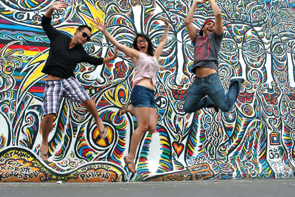 Three students jumping in front of mural, East Side Gallery