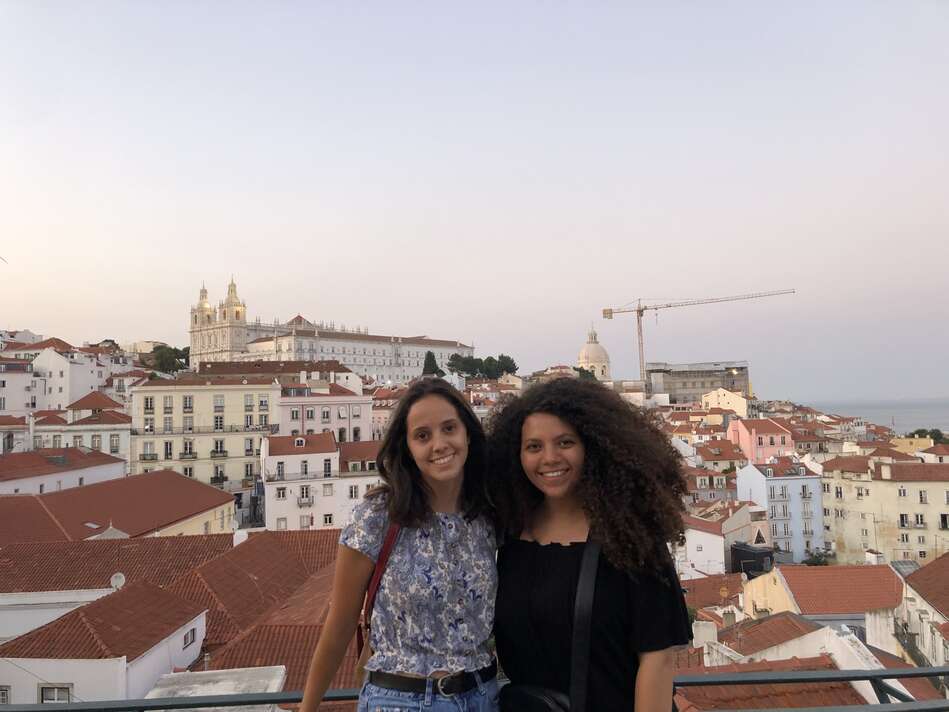 Two students in front of Portas do Sol during sunset