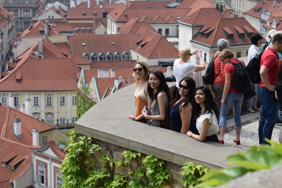 Four female students on balcony overlooking city view of Prague