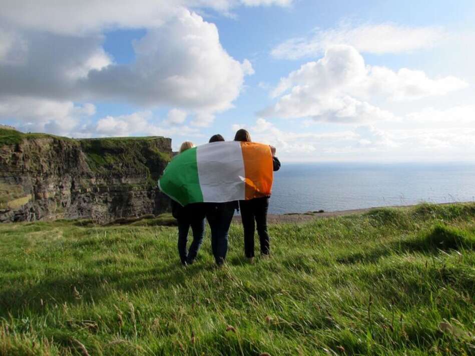 Back view of students with Irish Flag, on coast by water