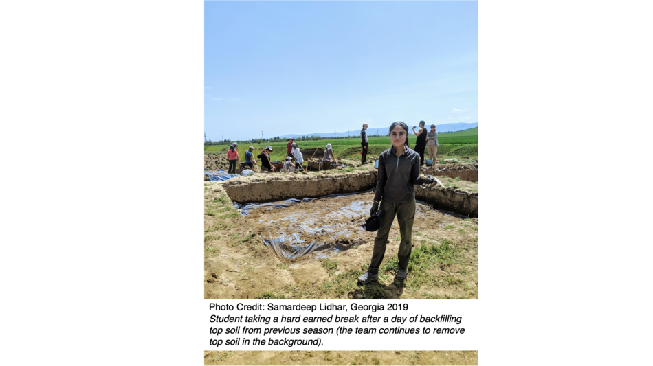 Student taking a hard earned break after a day of backfilling top soil from previous season (the team continues to remove top soil in the background).